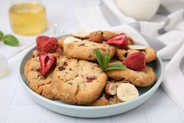 Cookies with freeze dried fruits, mint and nuts on white tiled table, closeup