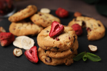 Obraz na płótnie Canvas Cookies with freeze dried fruits, mint and nuts on black board, closeup