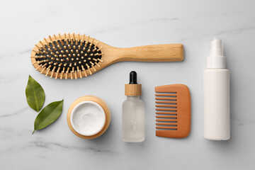 Flat lay composition with wooden hair brush and comb on white marble table