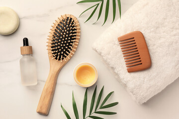 Flat lay composition with wooden hair brush and comb on white marble table - obrazy, fototapety, plakaty