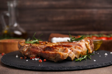 Pieces of delicious fried meat with rosemary and spices on table, closeup