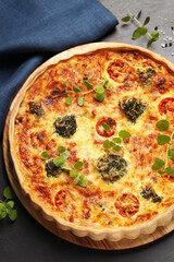 Delicious homemade vegetable quiche on dark table, top view
