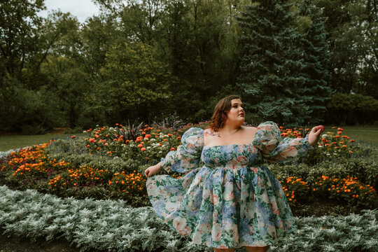 portrait of a plus size woman holding a macaron in a garden