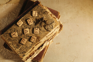 Wooden runes and old books on beige table, top view. Space for text