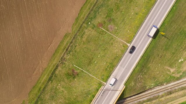 Drone pov footage of various vehicles on highway through cultivated landscape, directly above