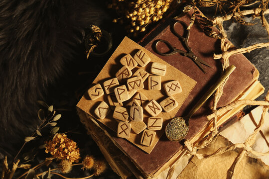 Many wooden runes, dried flowers and old books on altar, flat lay