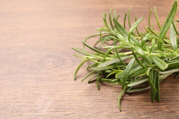 Fresh green rosemary on wooden table, closeup. Space for text