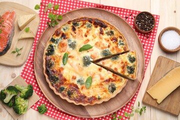 Delicious homemade quiche and ingredients on table, flat lay