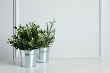 Aromatic potted herbs on wooden table near white wall, space for text