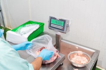 Worker pack the chicken parts in bags and weighing them.