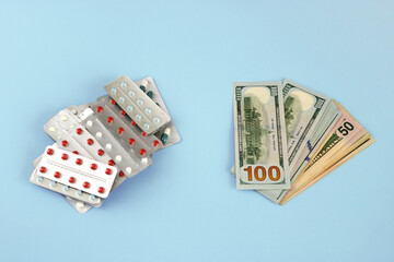 lot of pills and a stack of money on a blue background, the high cost of treatment