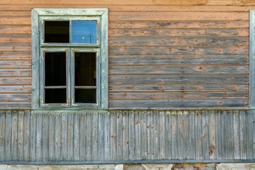 An old ruined wooden house in the village. Details of the facade of a historic wooden house with carved shutters and vintage decor elements.