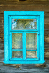 Wooden blue window shutters on the wall of an old dilapidated wooden house in the village. The destroyed abandoned dwelling after the cataclysm.