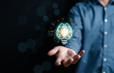 Businessman holding virtual lightbulb with brain icon, idea, innovation and inspiration with glowing virtual brain, smart intelligent creativity with bulbs, Motivation and innovation concept
