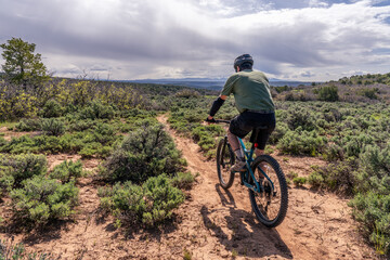 Fototapeta na wymiar Matured Caucasian man riding away a mountain bicycle on a sandy path, Lower Sage Hen Trail Loop, McPhee Recreation Area, San Juan National Forest, Colorado