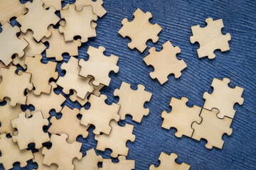background of blank wooden jigsaw puzzle pieces on blue paper  background, completing a task or...