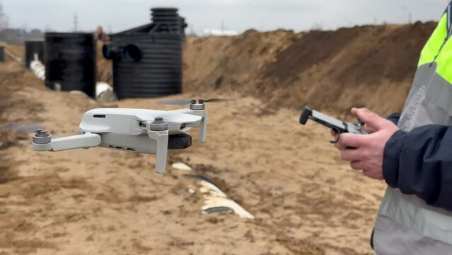 Geodesic quadcopter. A human surveyor. Launching a quadcopter over a construction site. The surveyor launches the drone. Geodetic works before construction. A surveyor in a protective helmet is sent