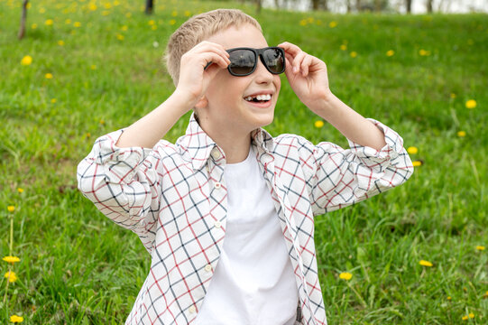 Cute boy with no tooth put on colorblind sunglasses and looks up
