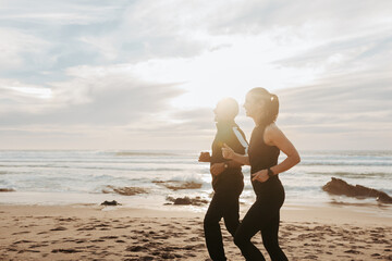 Happy mature caucasian man and woman in sportswear run in morning on sea beach, outdoor