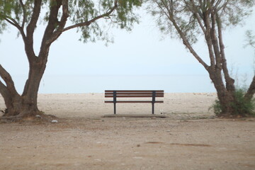 Fototapeta na wymiar Bench on the beach between the trees