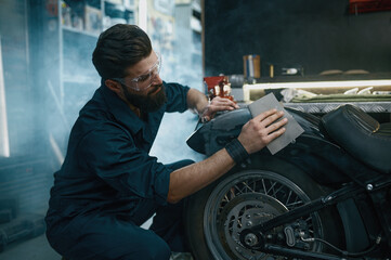 Young man repair service worker sanding motorcycle from old paint