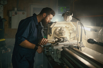 Serviceman working on turning lathe to adjust spare parts, repair work