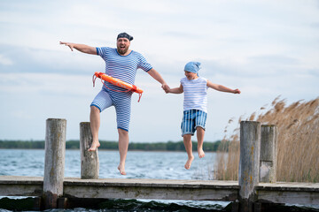 Vater und Sohn springen vom Steg in den See