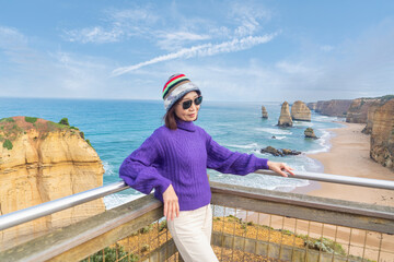 Fototapeta na wymiar Middle-aged Asian woman backpacking backpacker excitedly arrives at her destination Port Campbell National Park. Great Ocean Road, Victoria State, Australia.