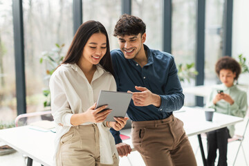 Cheerful Mixed Business Coworkers Couple Using Tablet Computer In Office