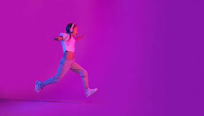 Preteen girl running towards copy space, using headphones