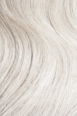 Blond hair close-up as a background. Women's long blonde hair. Beautifully styled wavy shiny curls....