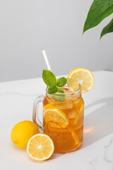 A glass of cold tea, ice cubes, lemon slices and a sprig of mint. Cooling summer drinks.