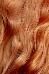 Naklejka premium Red hair close-up as a background. Women's long orange hair. Beautifully styled wavy shiny curls. Hair coloring bright shades. Hairdressing procedures, extension.
