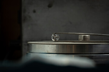 close up photo of round Diamond in Tweezers on polishing surface