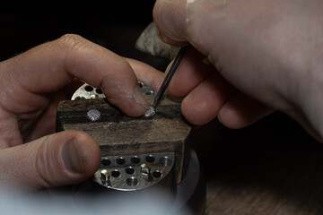 master of jewelry manually inserts gems into the frame of future jewelry. Working desk for craft jewelery making with professional tools.