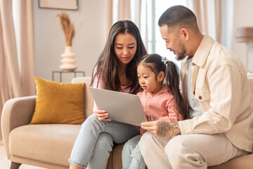 Korean Parents And Baby Daughter Using Computer At Home