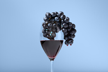 Copa de vino tinto con uvas negras sobre fondo azul