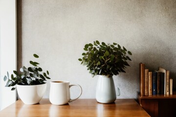 Silver green eucalyptus tree branches in beige textured vase. Brown cup of coffee, tea and old books on wooden table. White wall background. Minimalistic Scandinavian interior, dinning room