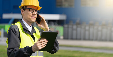 Logistician with phone and digital tablet on a background of logistic center