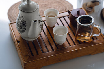 Obraz na płótnie Canvas the concept of an Asian tea set with a white tea set of cups and a teapot with fresh tea on a wooden tray
