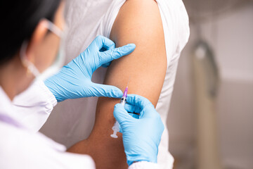 Doctor hand in blue gloves holding influenza vaccine for prevention human.Nurse holding syringe make injection in shoulder of patient in hospital.Covid-19 or coronavirus vaccine. - obrazy, fototapety, plakaty