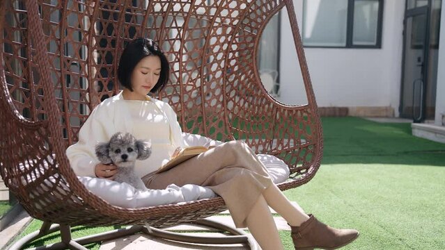Happy young Chinese woman with pet dog on hanging-chair,4K