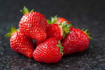 Strawberry. Wet ripe strawberries on a black background with water drops.  Brilliant glare. Selective focus