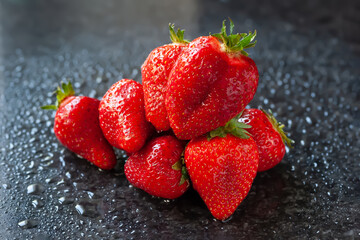 Bunch of strawberries. Wet ripe strawberries on a black background. Red berries with drops of water. Selective focus