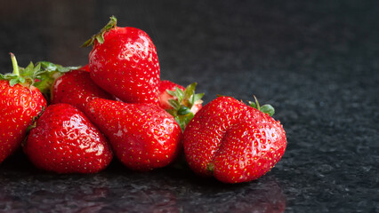Wet strawberries. A bunch of wet ripe strawberries with water drops on a black background. Red berries. Selective focus