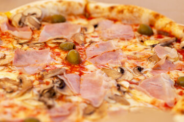 Fresh tasty pizza with bacon, mushrooms and olives with rim close-up. Selective focus, defocus