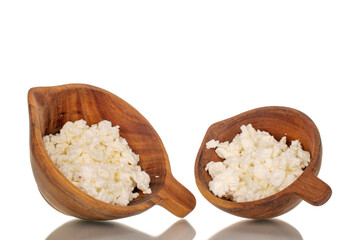 Fresh cottage cheese in two wooden cups, macro, isolated on white background.