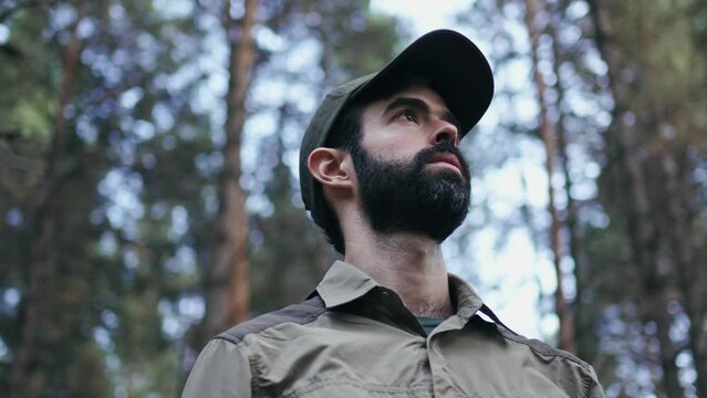 Young man wearing cap looking away in the forest. Park ranger during a surveillance wildlife