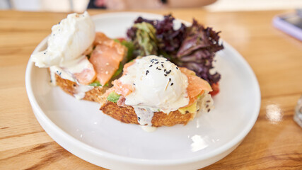restaurant dish Brioche with poached egg with salmon and avocado. Delicious bread with greens