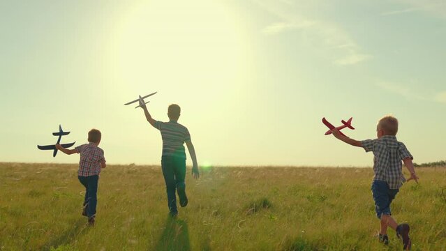 Dream travel, fly. Children play run with toy airplane in their hand sunset. Boy child plays airplane pilot. Children friends running with toy airplane, park. Childrens flight to future. Family travel